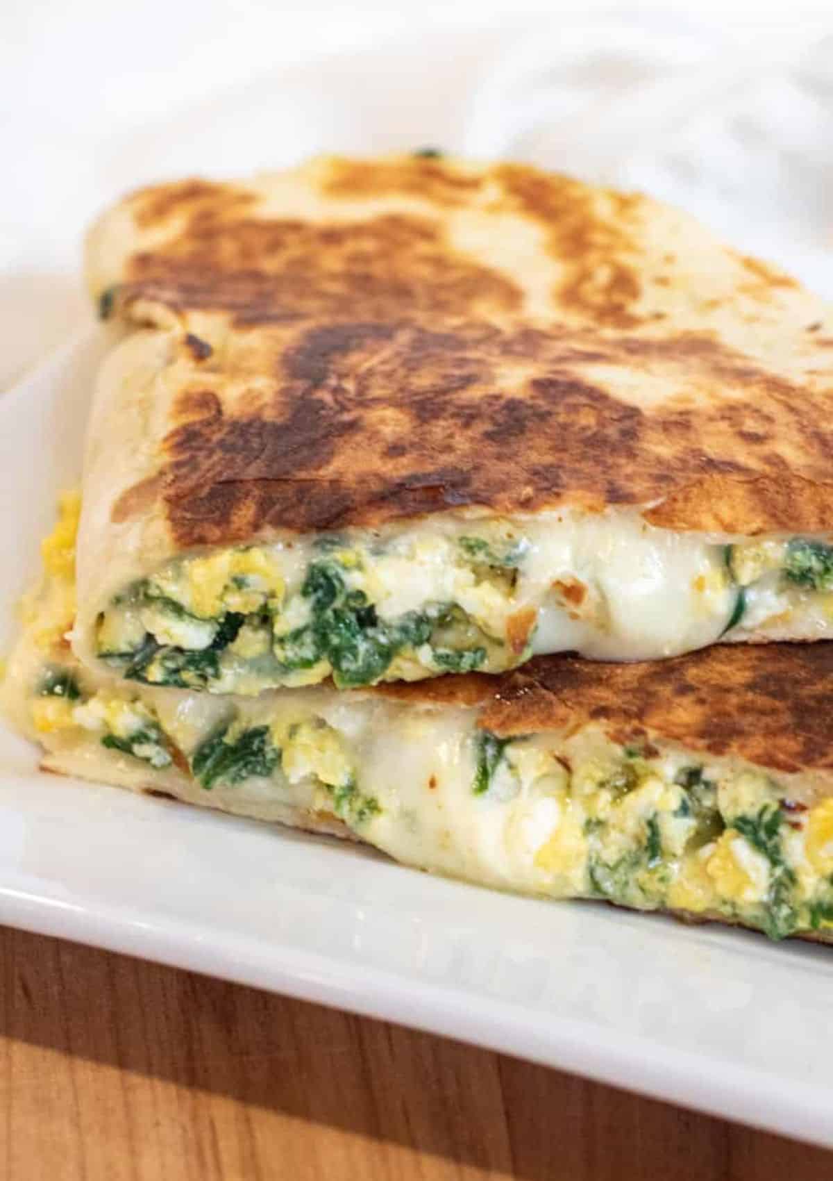 A toasted brown tortilla with scrambled eggs, feta cheese inside.
