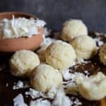 Balls of white coconut on a serving platter with chunks of coconut all around.