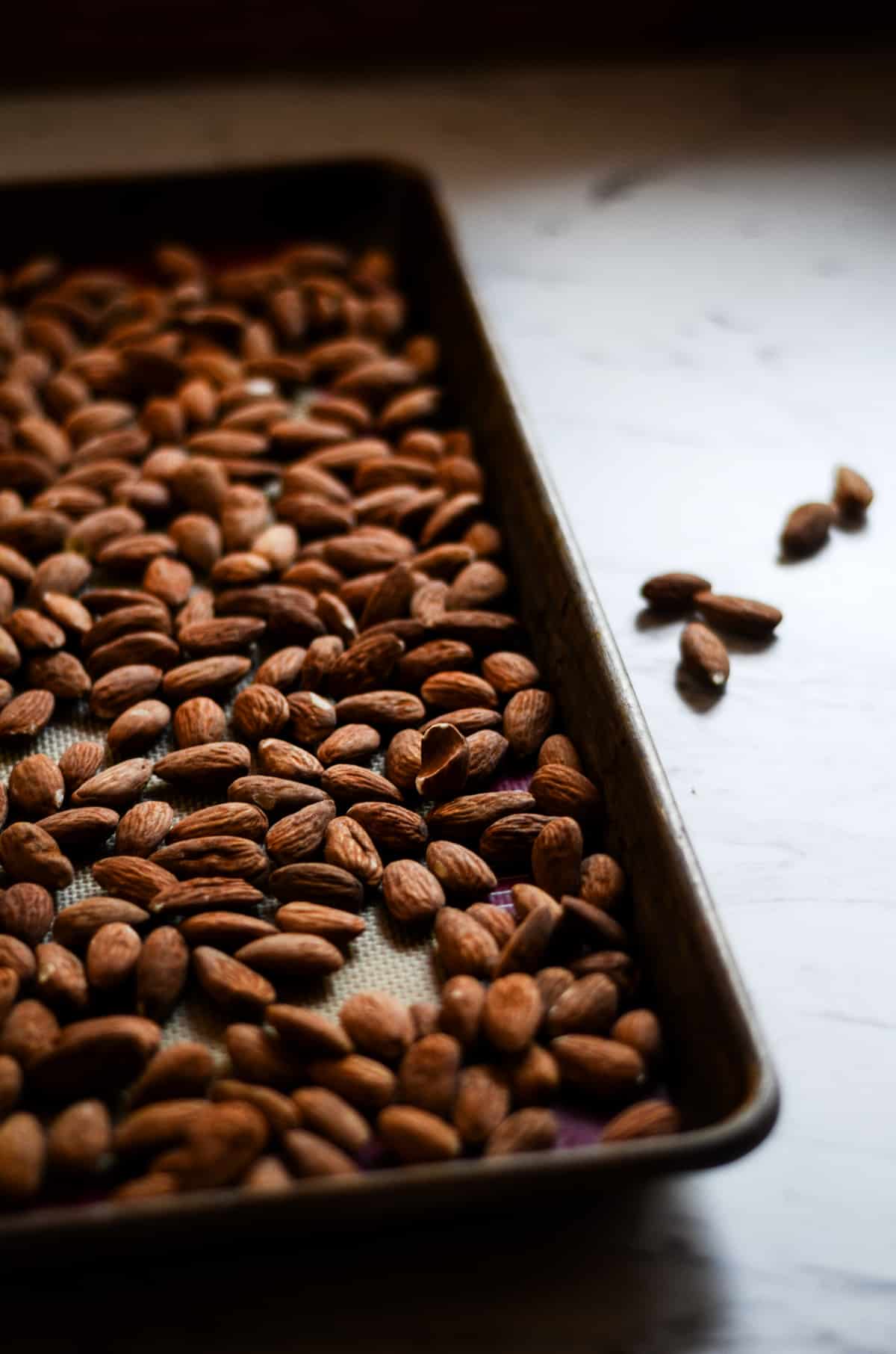 Raw organic almonds on a cookie sheet ready to be toasted in the oven.