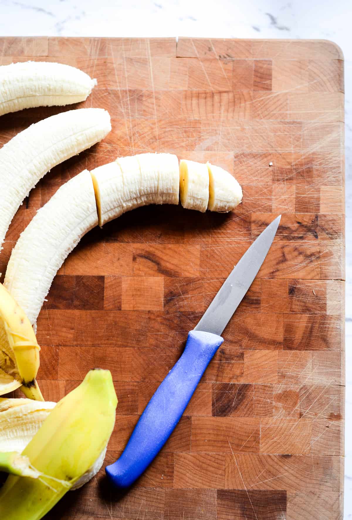 A banana on a cutting board being sliced.