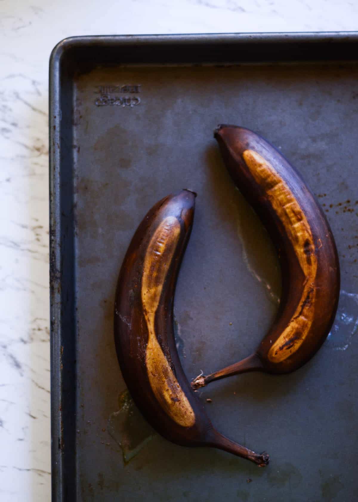 Fully brown and black bananas on a cookie sheet.