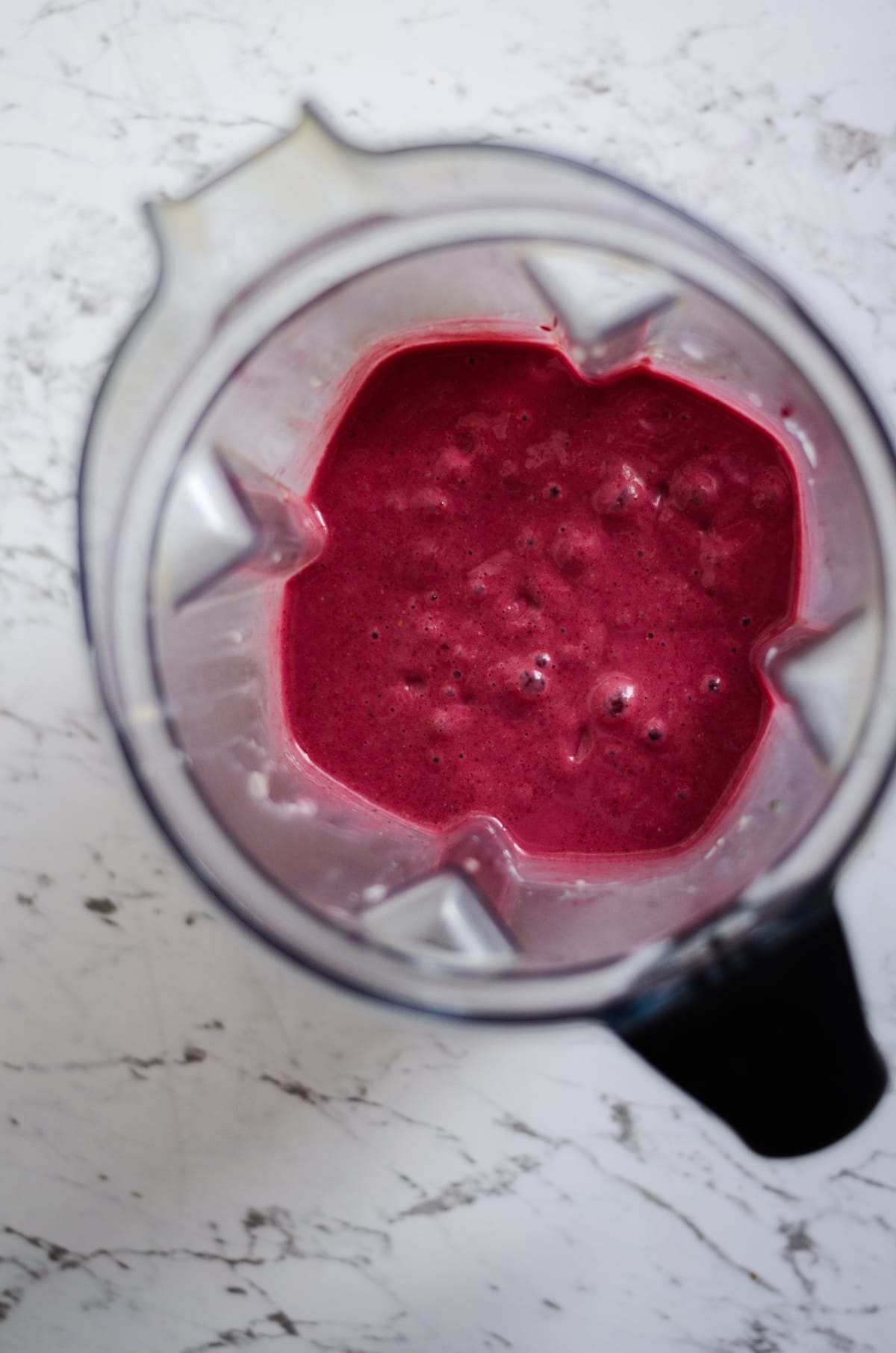 Creamy pink raspberry smoothie in a vitamix blender container.