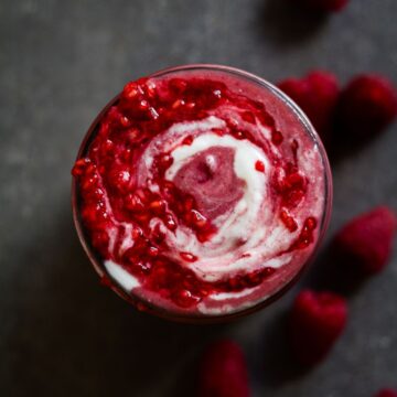 A beautiful raspberry smoothie with yogurt and raspberry swirl on top.