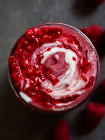 A beautiful raspberry smoothie with yogurt and raspberry swirl on top.