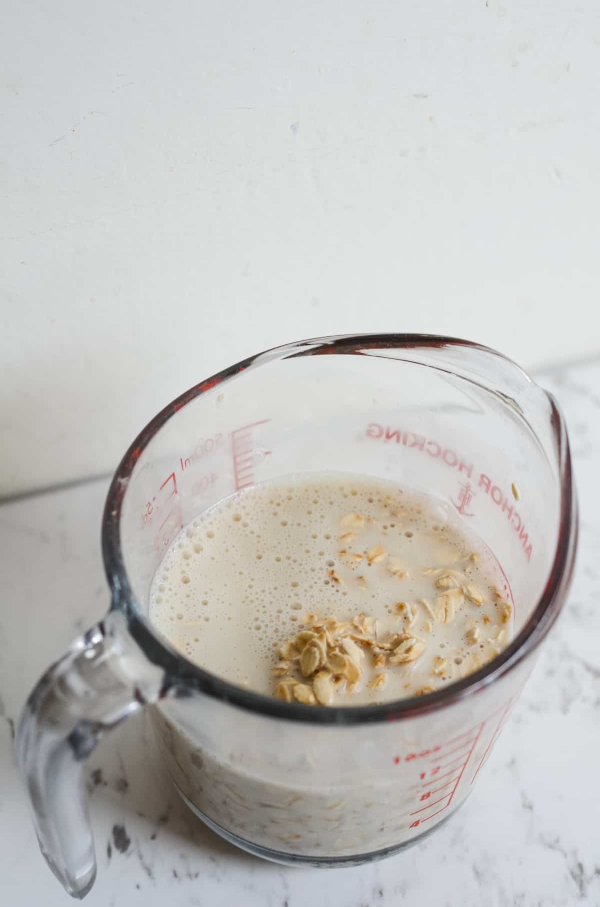 Milk and rolled oats in a measuring cup.