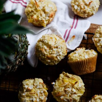 Yellow muffins with toasted coconut on top, and a a fresh pineapple beside them.