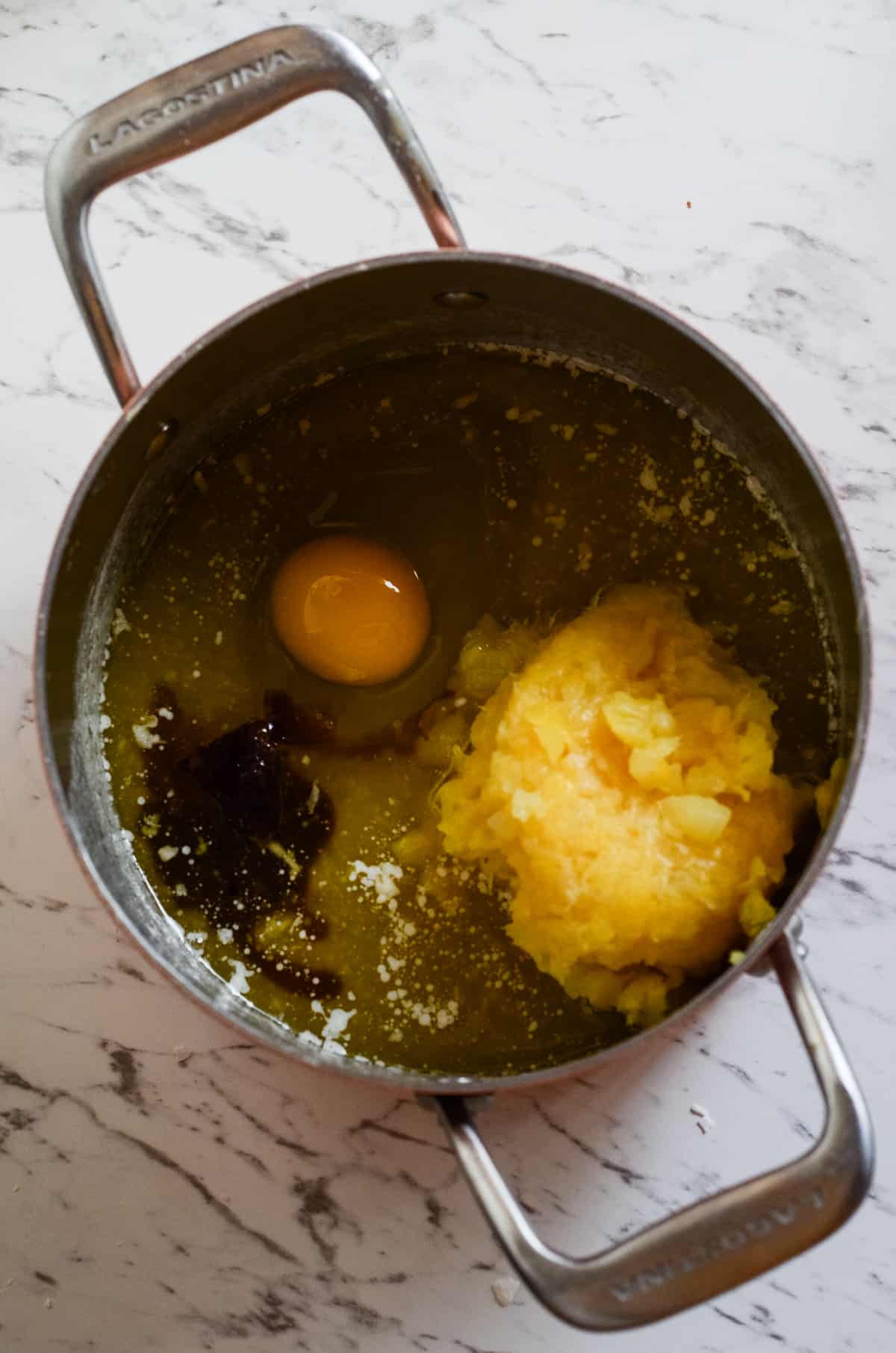 Melted butter, egg, crushed pineapple, and vanilla in a pot.
