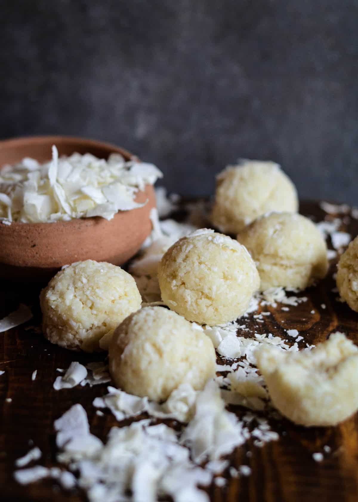 Raw coconut balls on a platter with large chunks of coconut all around.