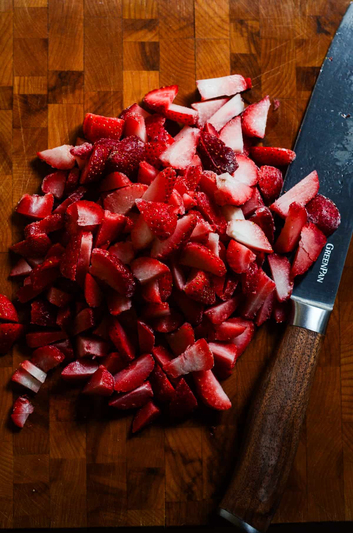 Frozen strawberries on a cutting board.