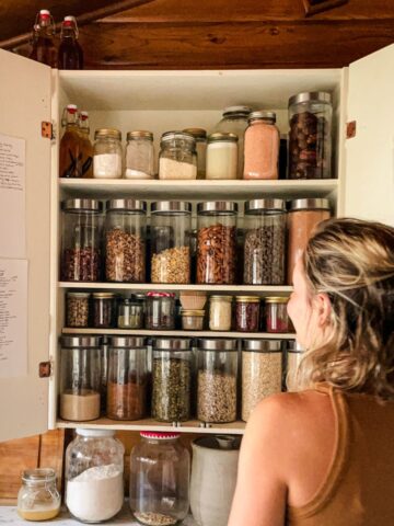 Nutritionist looking into her cupboard with healthy food ingredients in jars.
