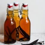 Light brown vanilla in swing top bottles with vanilla beans inside.
