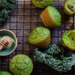 Kale muffins on the cooling rack with fresh kale beside it.