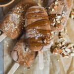 Fudgesicles sitting on parchment paper with almond sea salt caramel swirled on top.