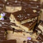 Stacked cookie dough bars with chocolate on top and sea salt.