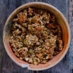 A pottery bowl with granola in it that contains pumpkin seeds and oats.