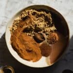 Cinnamon, ginger, nutmeg, cloves, allspice in a pottery bowl.