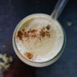 A light brown smoothie with tahini swirled into it with a sprinkle of cinnamon of top.