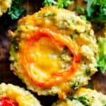 A close up of a quinoa egg bite with a orange banana pepper on top with kale around it.