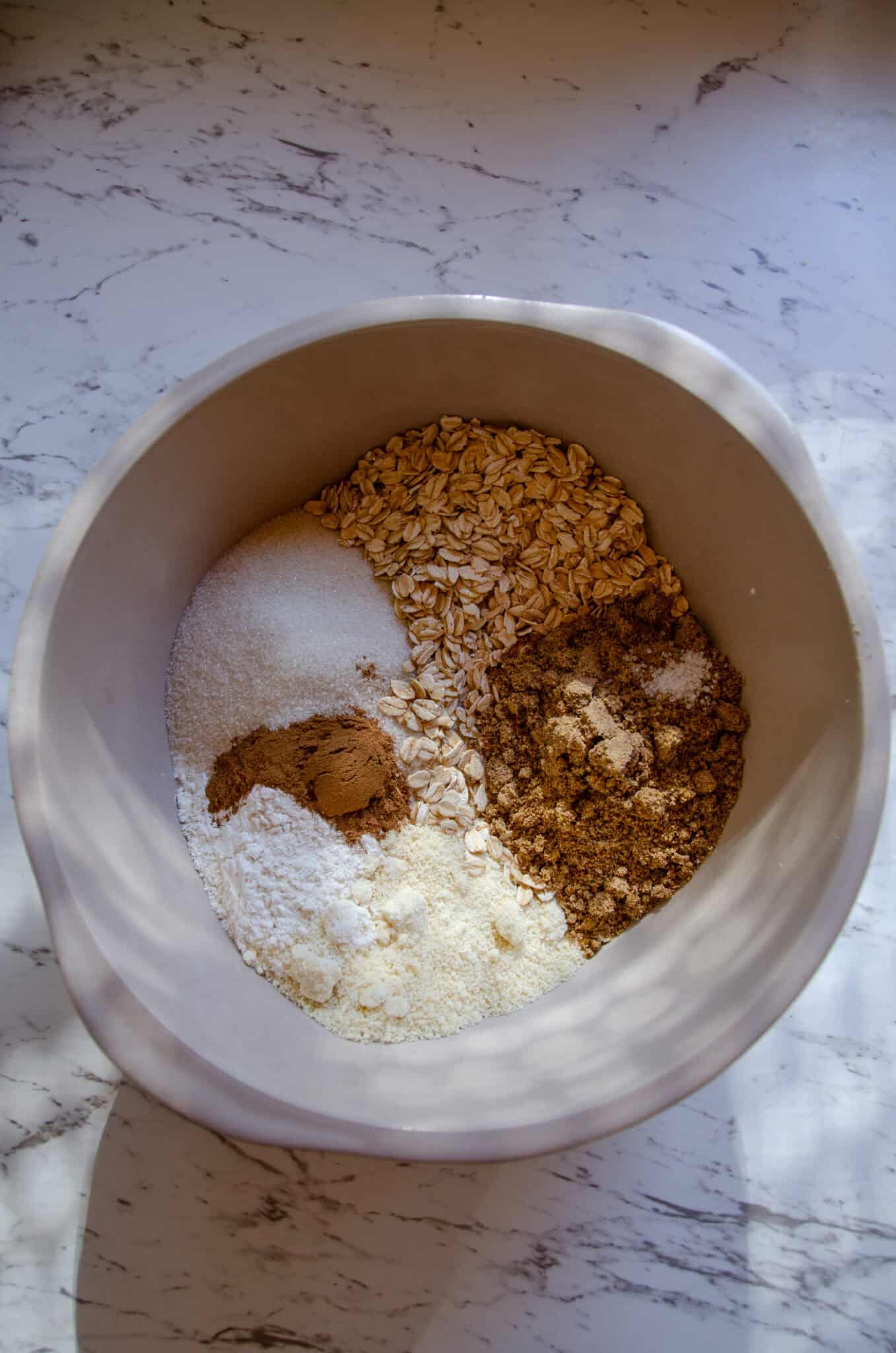 Flour, cinnamon, baking soda, oats, white sugar, brown sugar in a bowl.