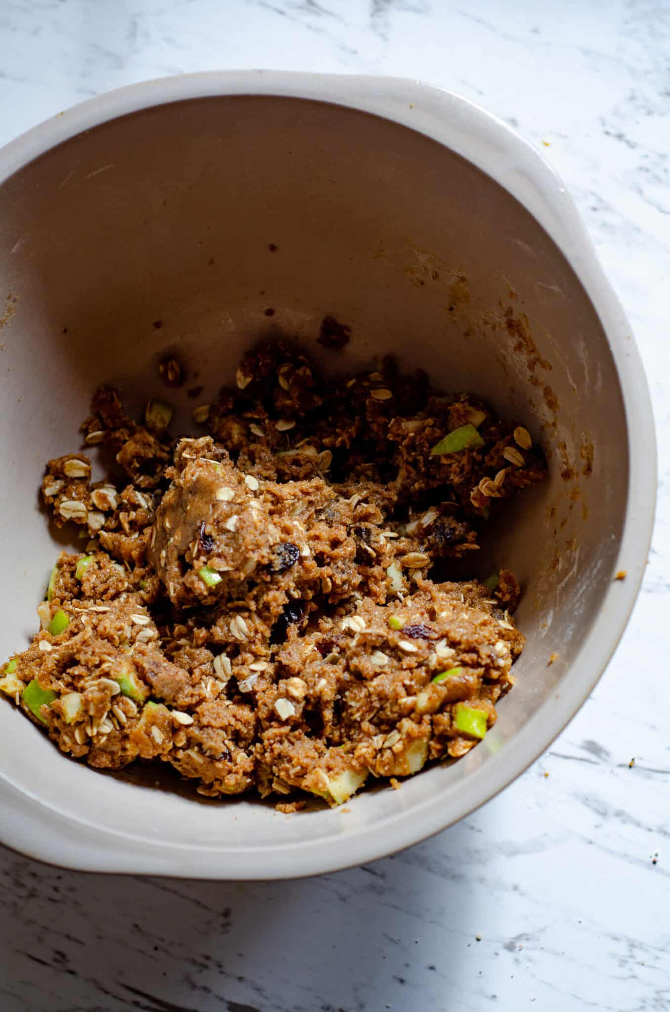 Thick cookie dough with pieces of apple, raisins, oats poking through.