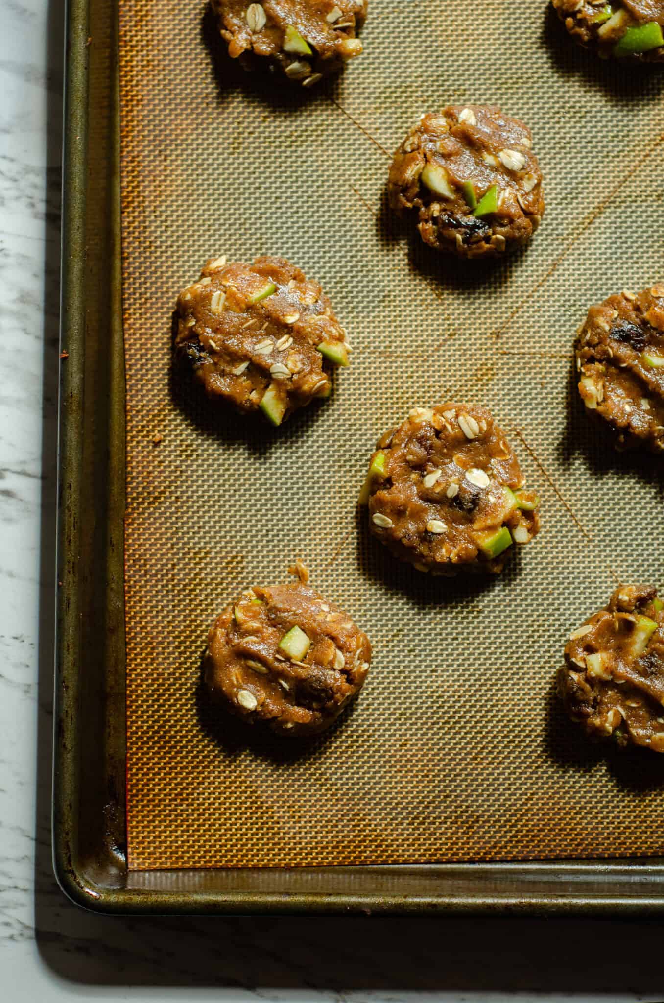 Cookie dough balls on cookie sheet with a silicone mat.