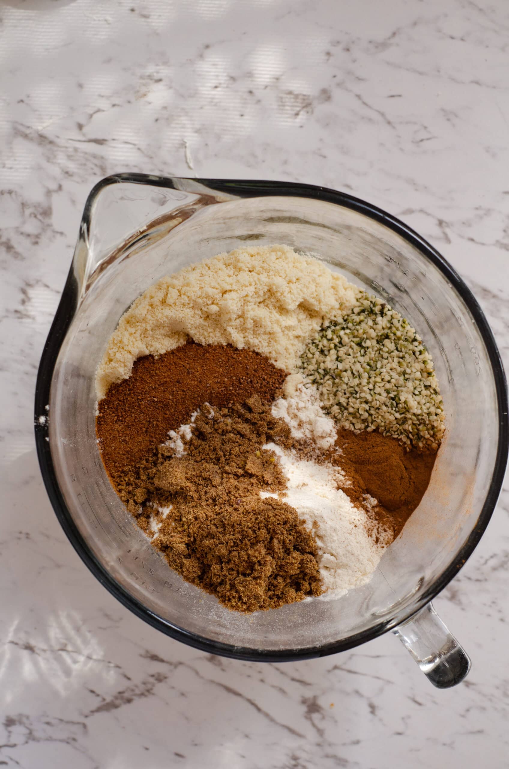 Hemp hearts, almond flour, cinnamon, baking soda, baking powder, ground flax in a glass mixing bowl.