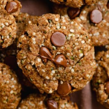 A pile of cookies with melted chocolate chips on top with hemp hearts.