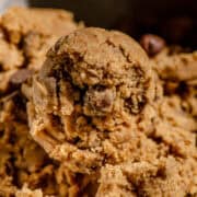 A scoop of cookie dough light brown with flecks of chocolate chips in it.