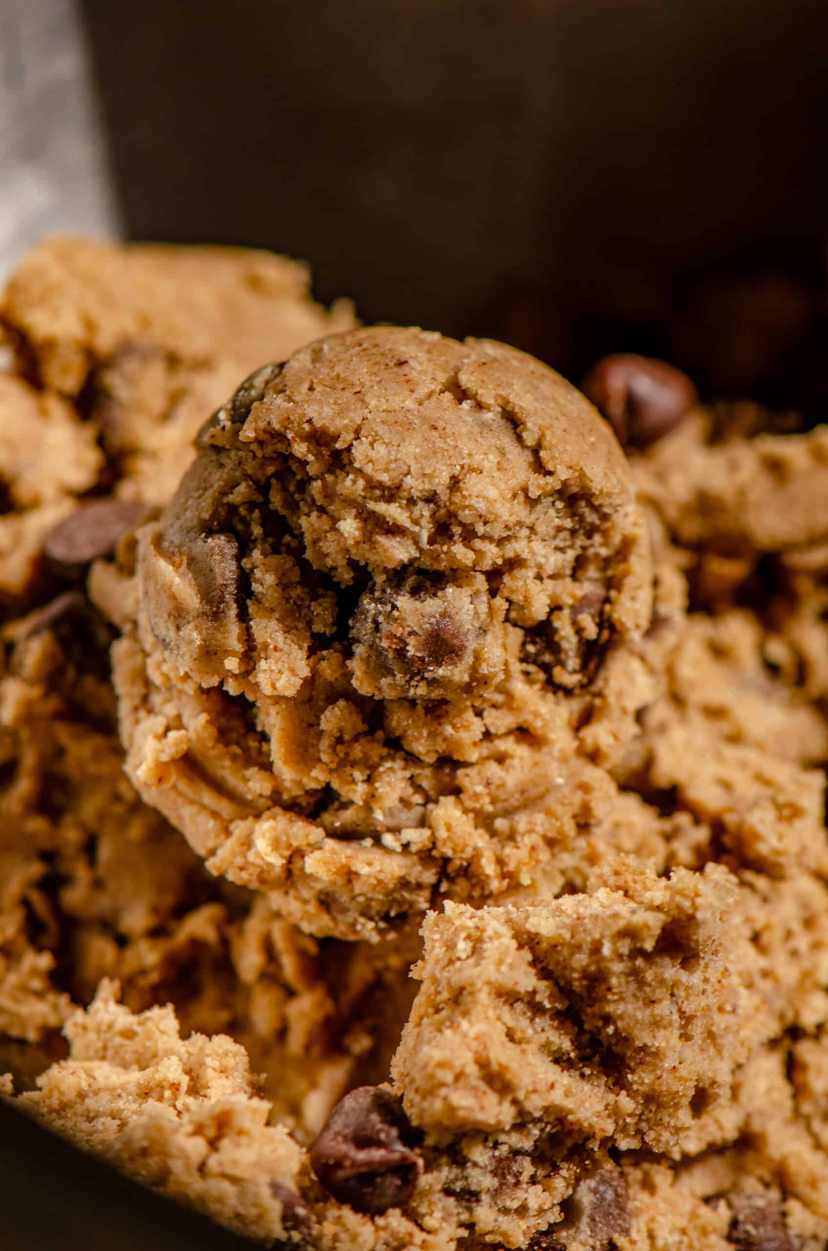 A scoop of cookie dough light brown with flecks of chocolate chips in it.