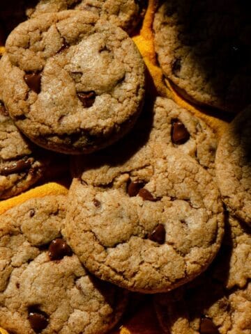 Fresh baked homemade whole wheat cookies with still melted chocolate chips in harsh lighting.