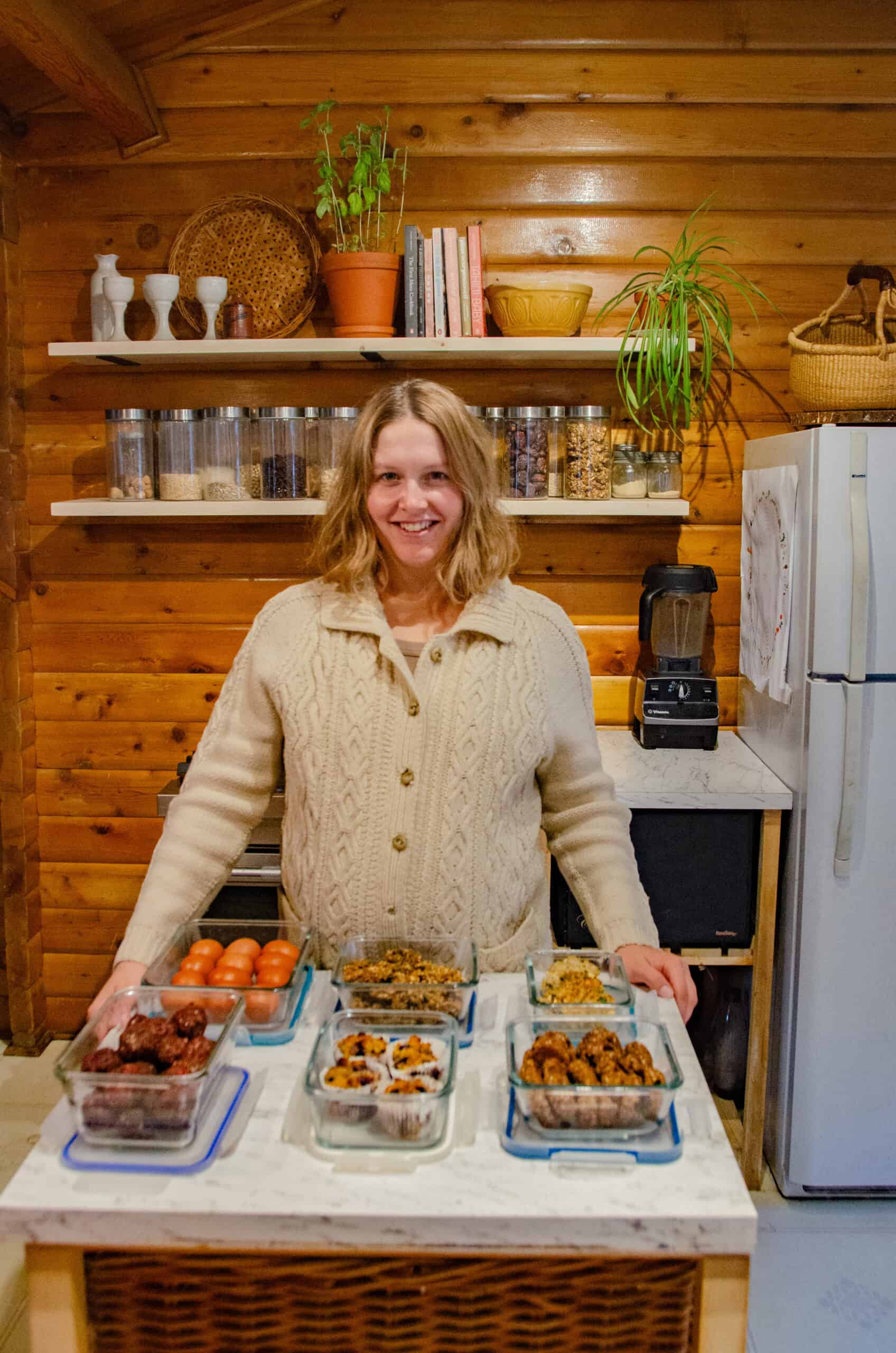 Nutritionist in her kitchen with glass containers of meal prepped snacks.