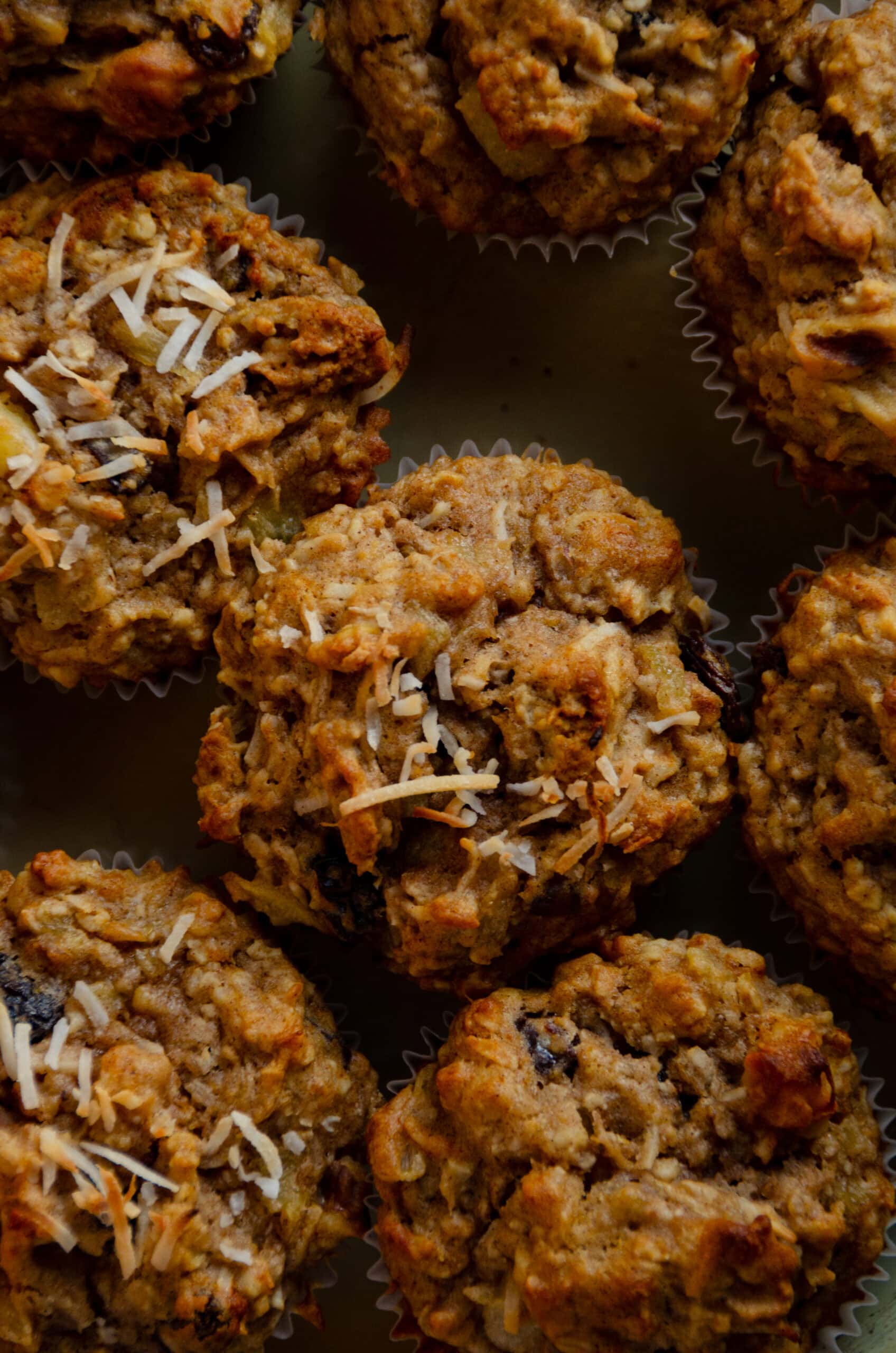 Light brown morning glory muffins with shredded coconut on top.