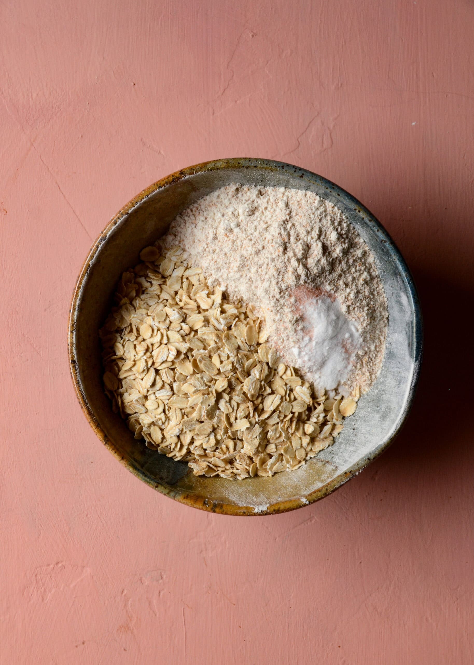 Oats, whole wheat flour, baking soda, and salt being mixed in a small bowl.