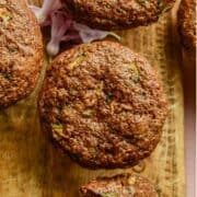 A brown muffins with green flecks on a cutting board.