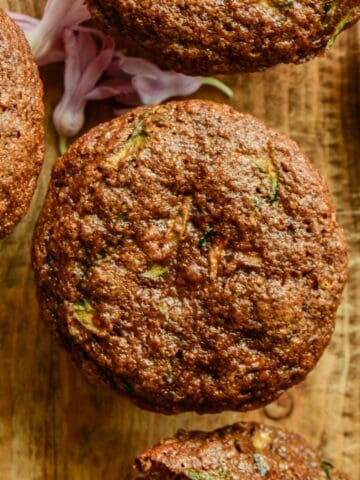 A brown muffins with green flecks on a cutting board.