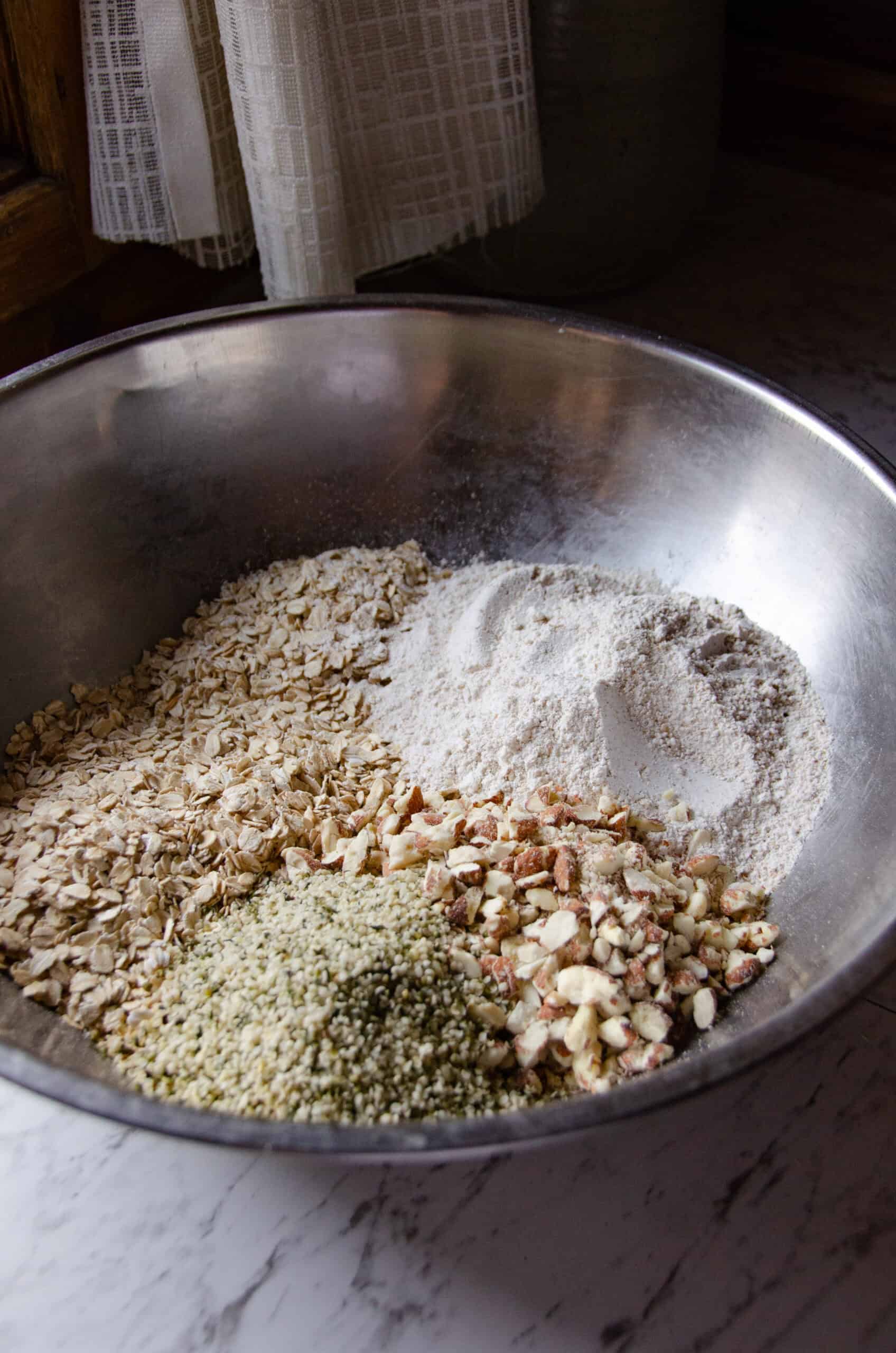 Oats, flour, hemp hearts, and almonds in a mixing bowl.