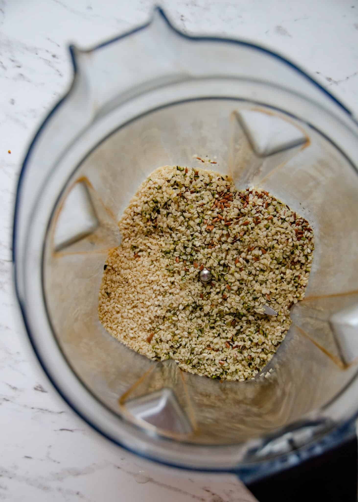 Sesame seeds, flax seeds, and hemp hearts in a blender container.