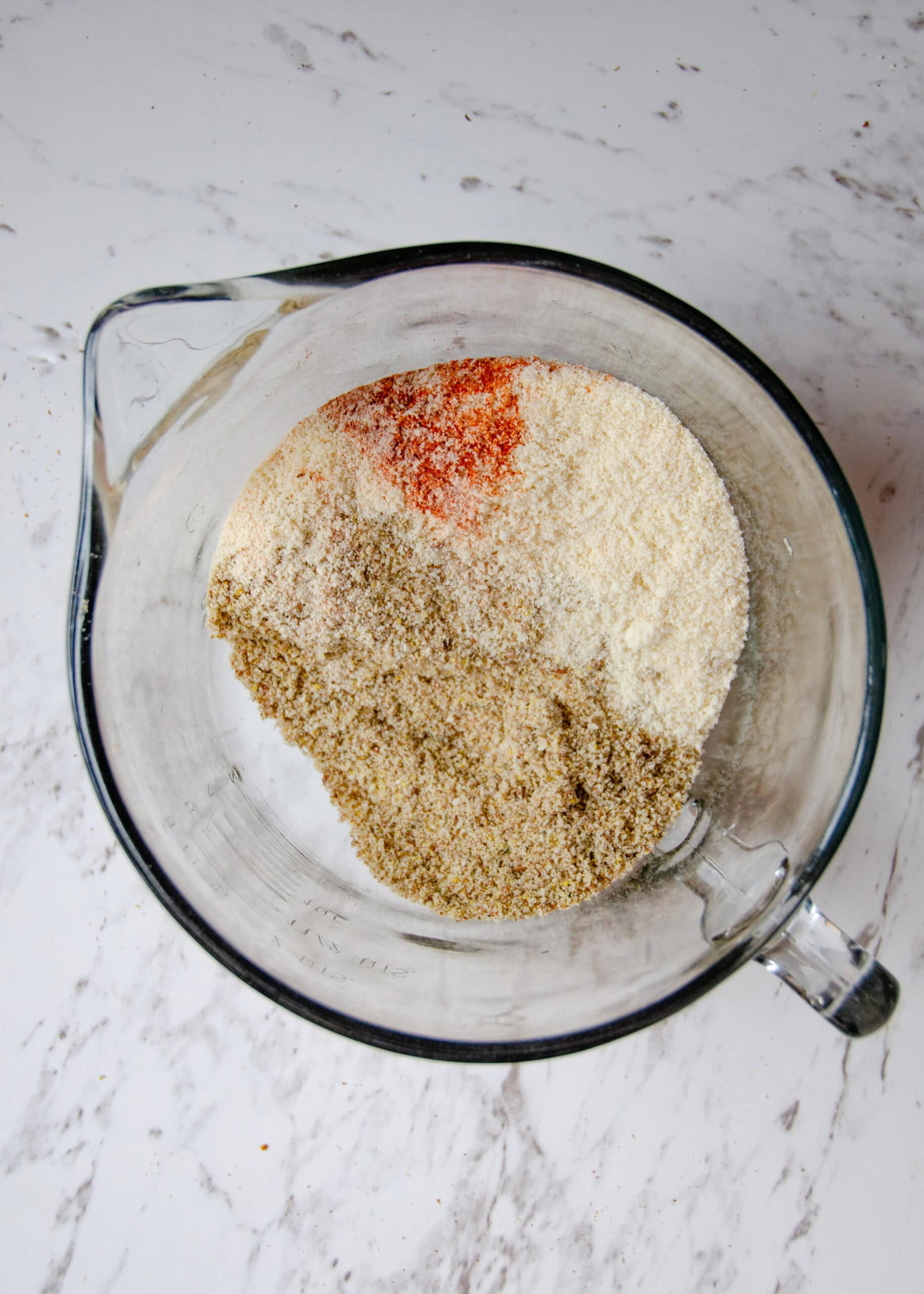 A bowl of ground up seeds, almond flour, red paprika for protein crackers.