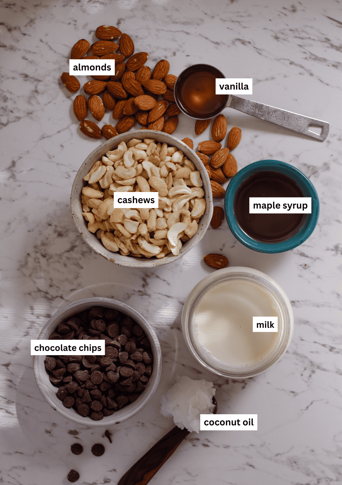 Ingredients for vegan magnum bars including almonds, maple syrup, cashews, vanilla, dairy free milk, coconut oil, and chocolate chips.