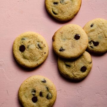 Soft and chewy chocolate chip cookies on a pink background.