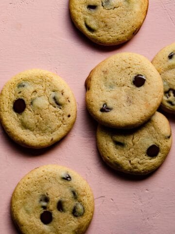 Soft and chewy chocolate chip cookies on a pink background.