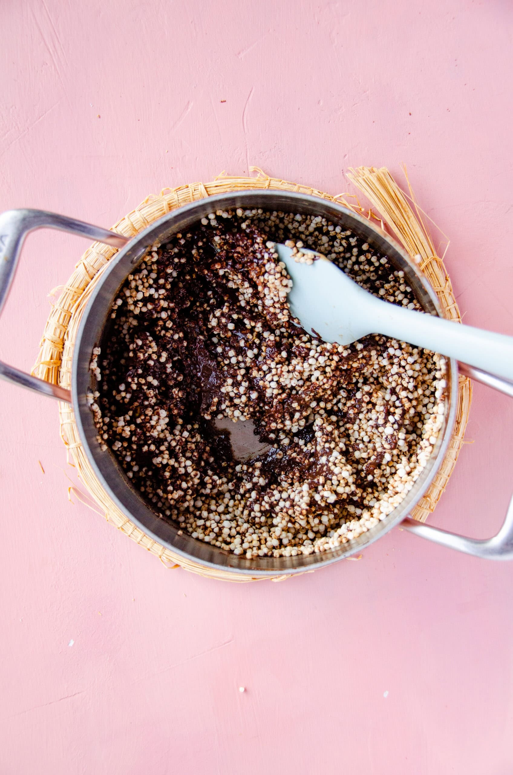 Toasted and puffed quinoa being added to a chocolate mixture in a pot.