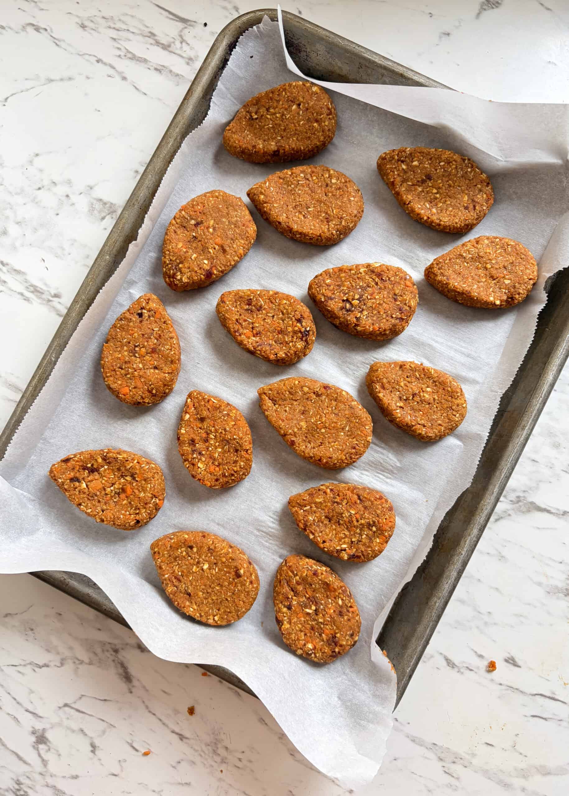 Egg shaped carrot energy balls on a cookie sheet.