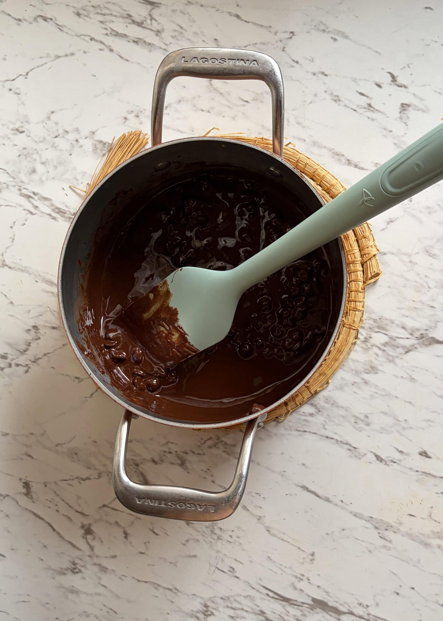 Melted chocolate in a small pot with a spatula.
