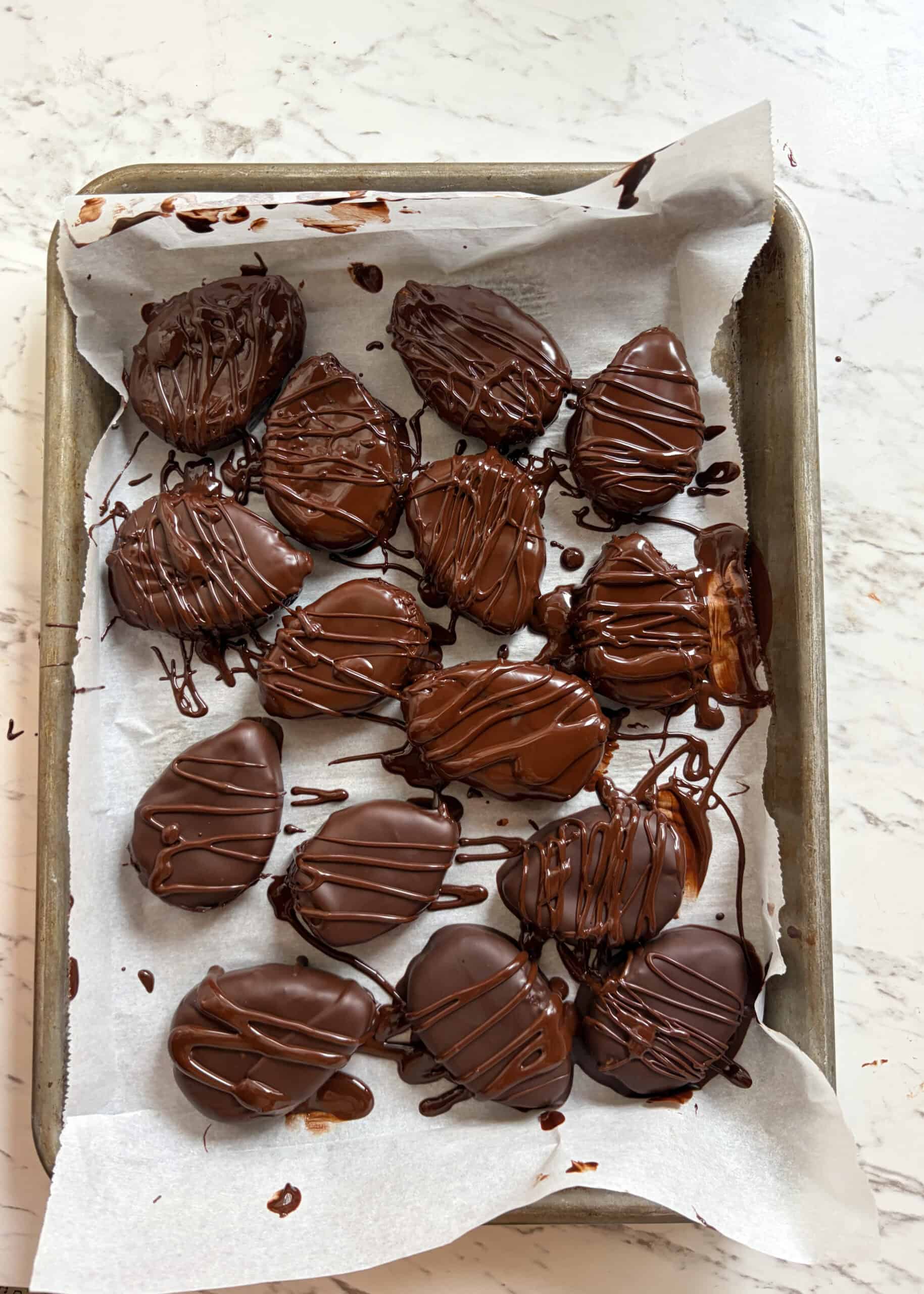 A cookie sheet with freshly coated easter eggs in chocolate.