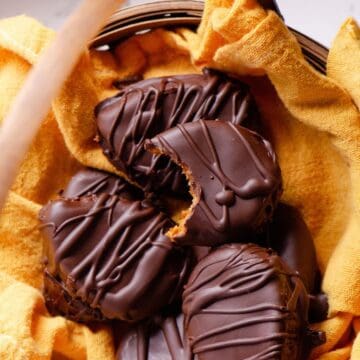 Chocolate easter eggs with a bite taken of of one showing an orange middle, in a straw easter basket.