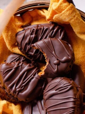 Chocolate easter eggs with a bite taken of of one showing an orange middle, in a straw easter basket.