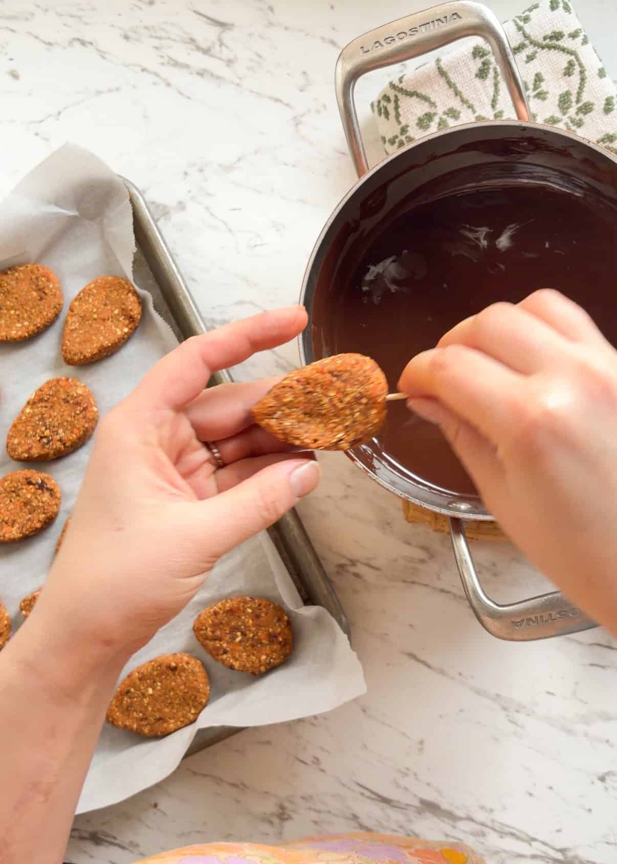 Placing a tooth pick into the egg shape dough and dipping it in dark chocolate.