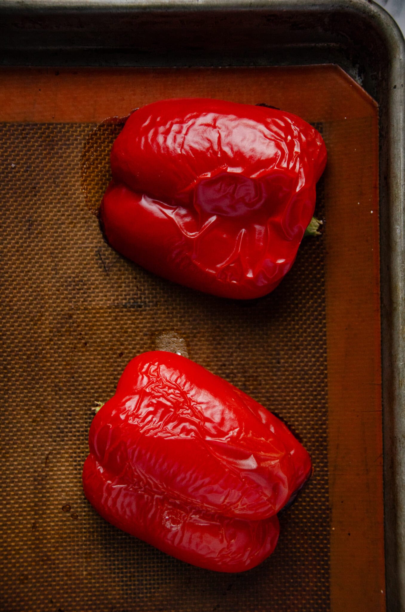 A roasted red pepper cut in half and on a cookie sheet.