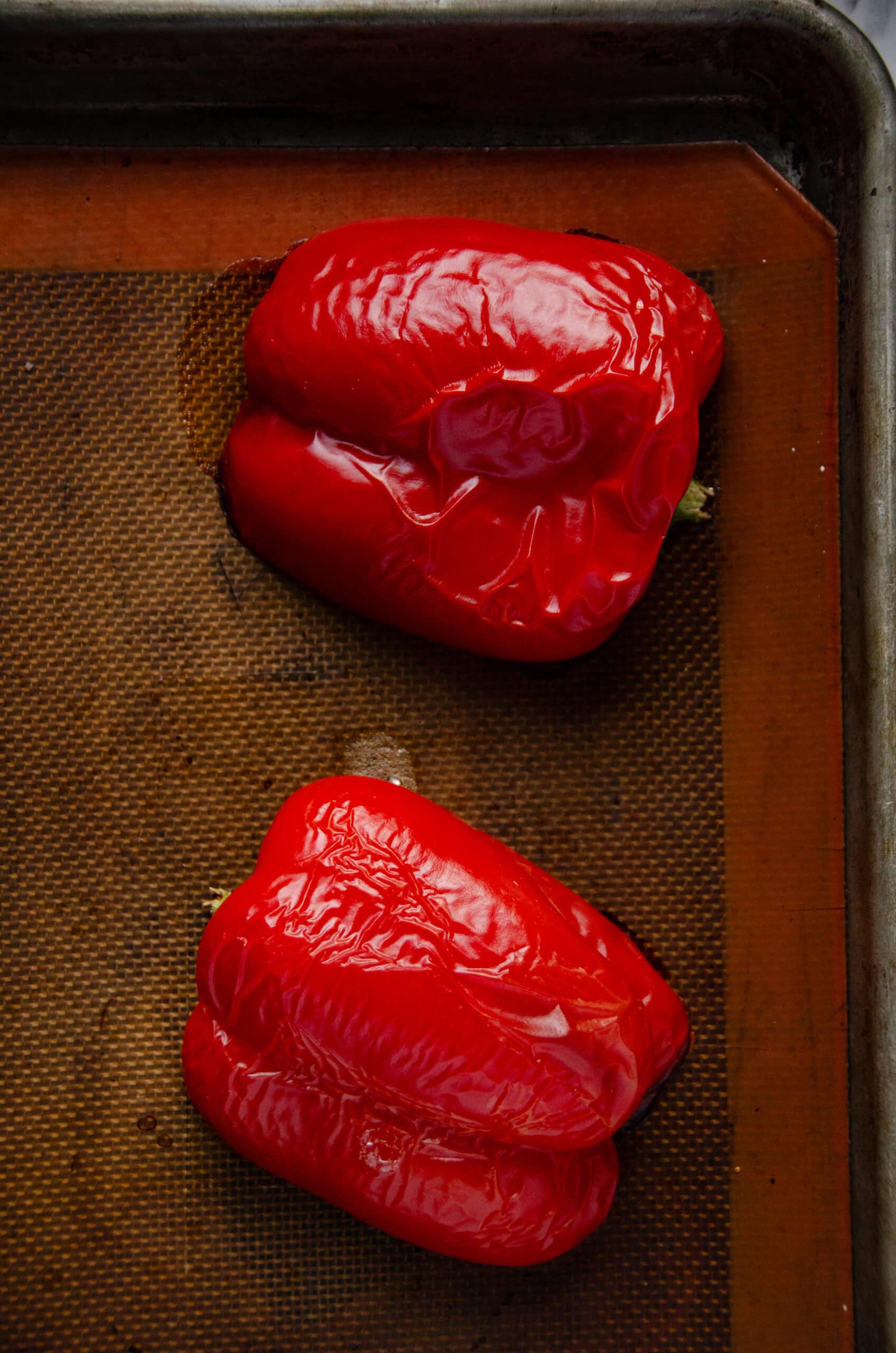 A roasted red pepper cut in half and on a cookie sheet.
